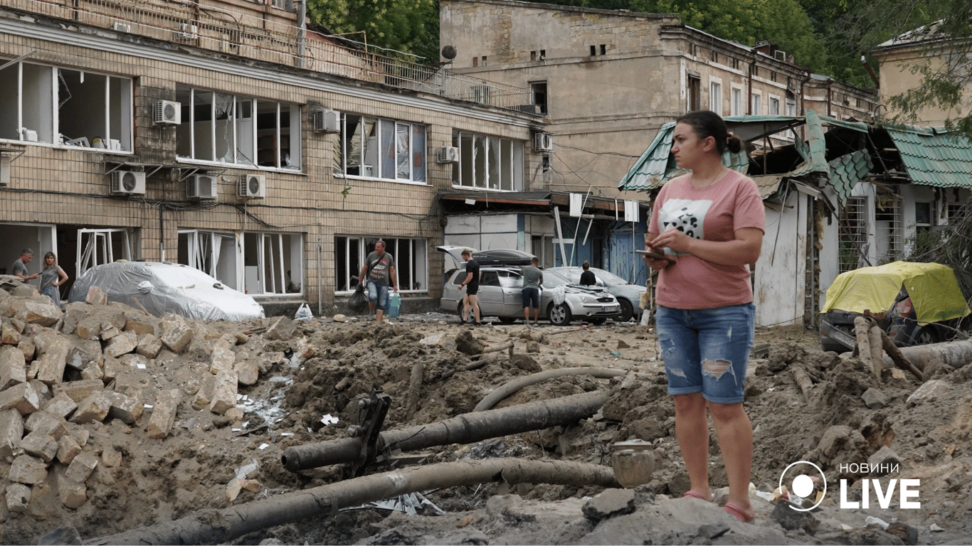 Женщина стоя на фоне разрушенной улицы. Фото: Новости.