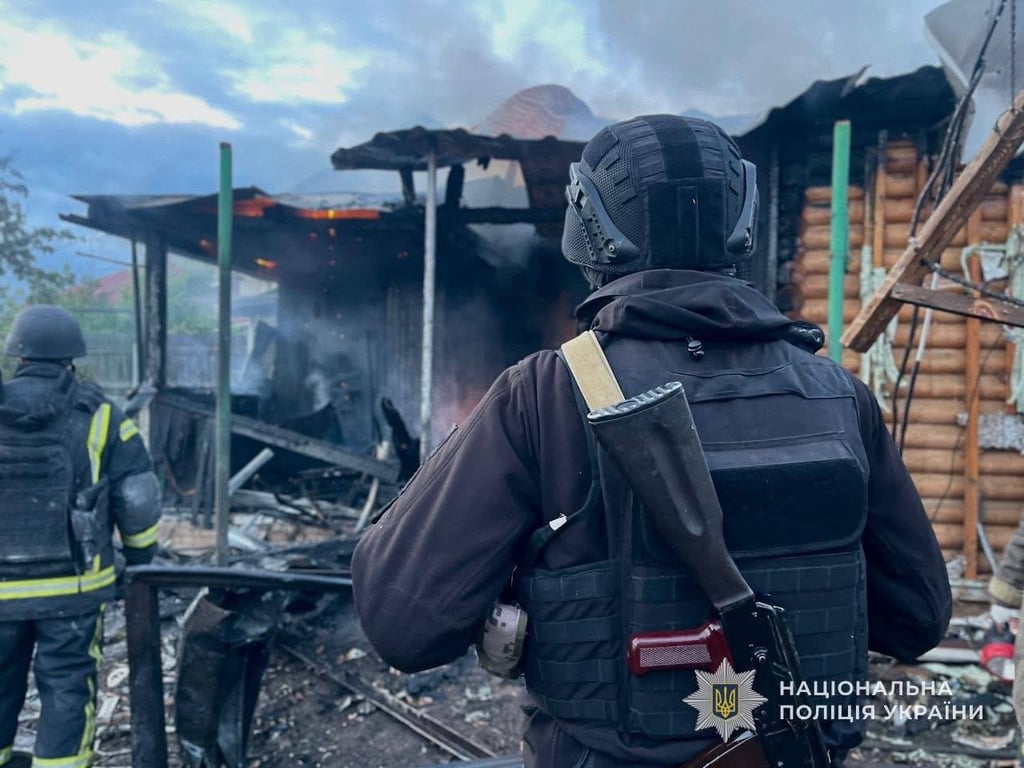 Поліцейський дивиться на розбиту обстрілом будівлю на Сумщині 31 травня