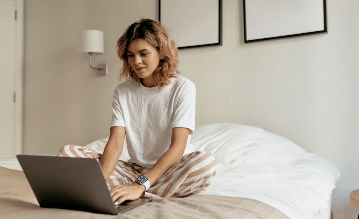 Молодая девушка, работающая за ноутбуком в постели