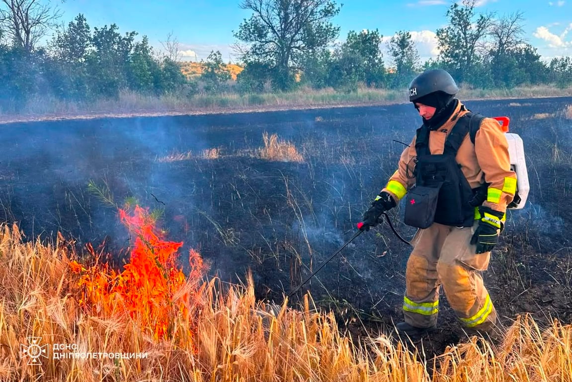 Пожежник гасить вогонь на полі з пшеницею, що постраждало в результаті ударів РФ по Дніпропетровській області 5 липня
