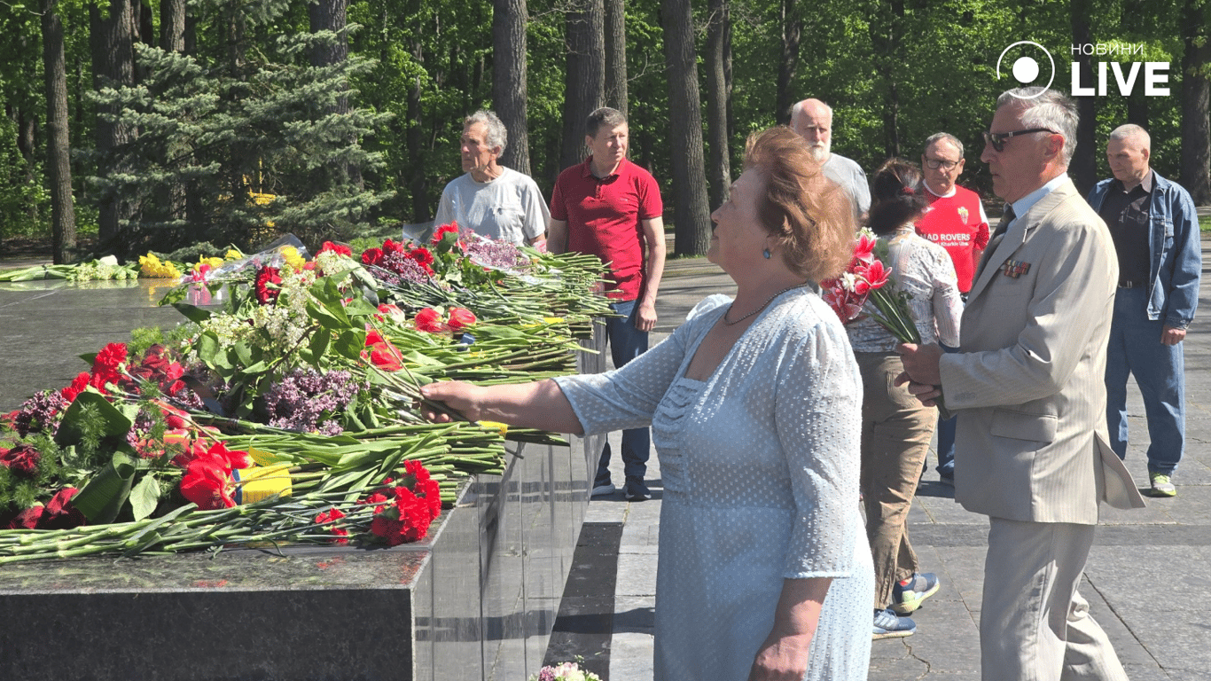 Жінка кладе квіти до меморіалу