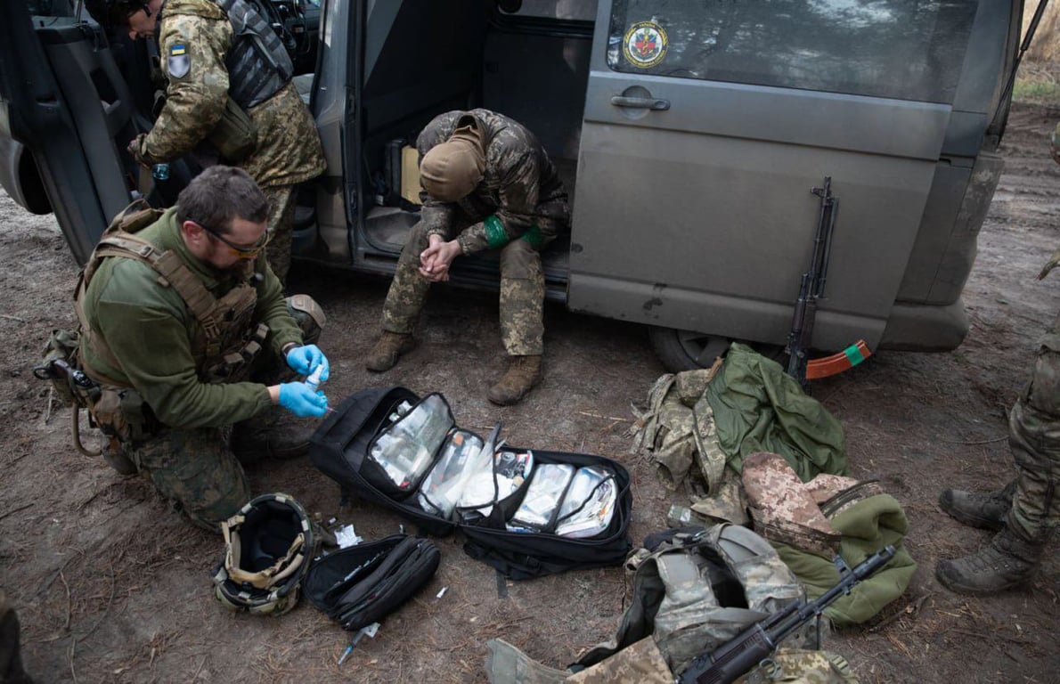Медик надає першу допомогу військовому