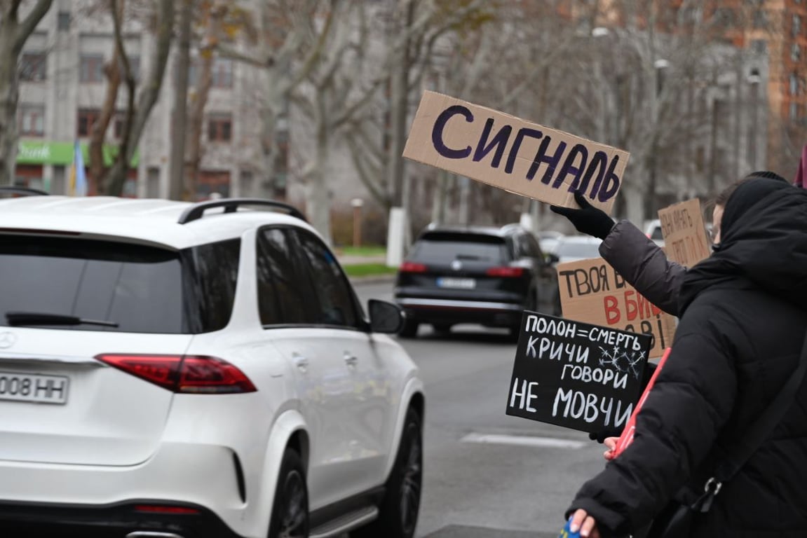 Учасник акції тримає плакат із написом “Сигналь” на проспекті Шевченка.