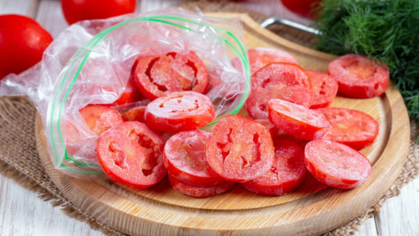 Заморожені нарізані помідори в пакеті на кухонній дошці.