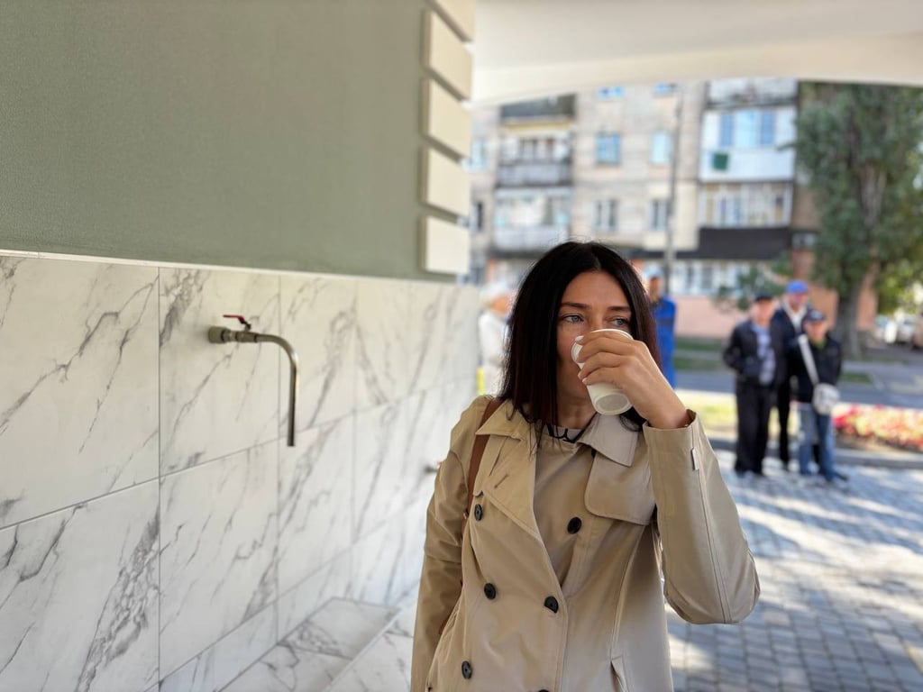 Жінка п'є воду з бювета