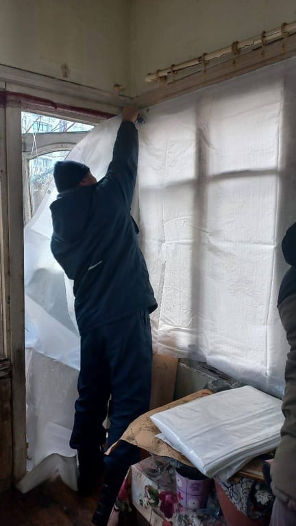 Чоловік закриває вікна плівкою