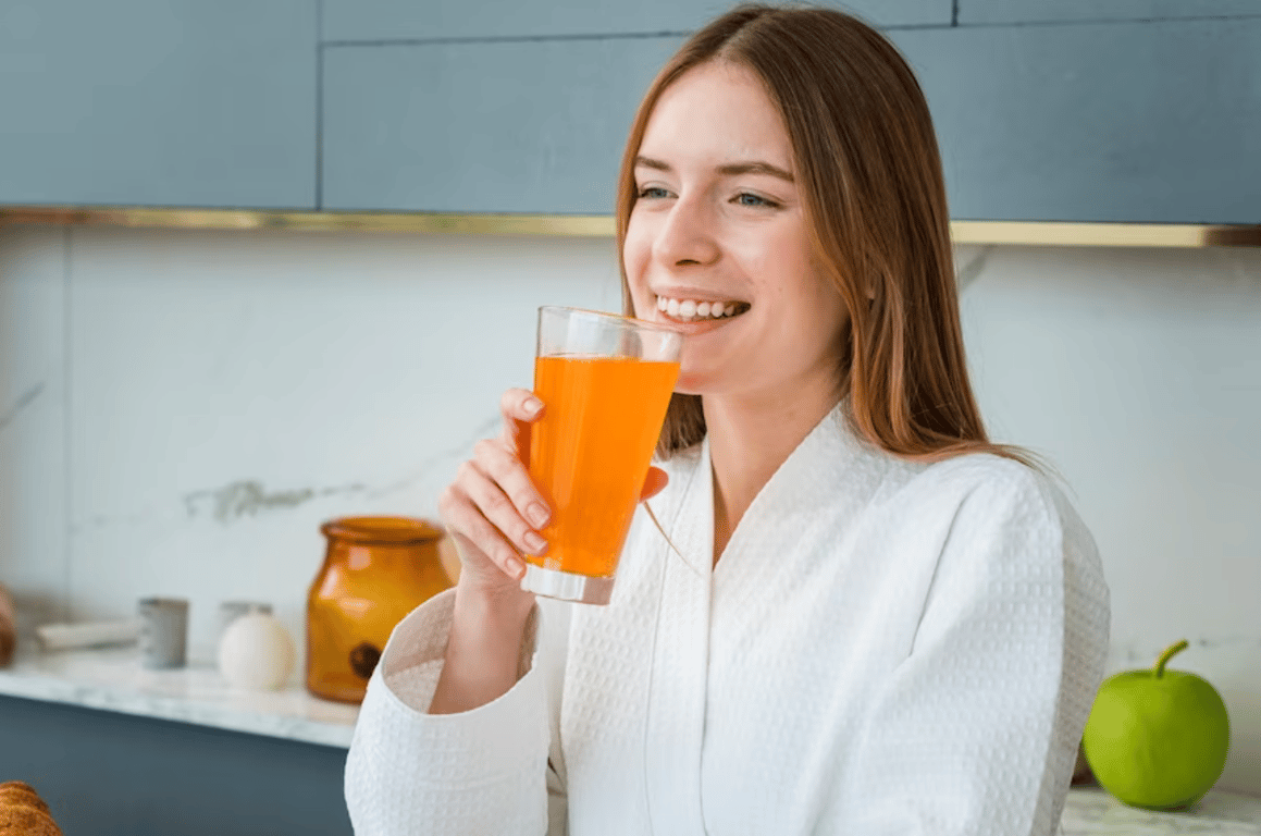 Счастливая молодая девушка, пьющая сок