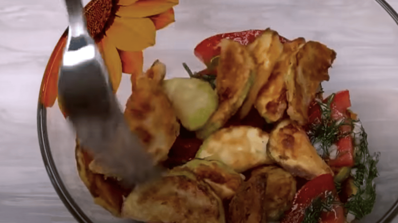 Шар салату з кабачків і помідорів, политий часниковою заправкою