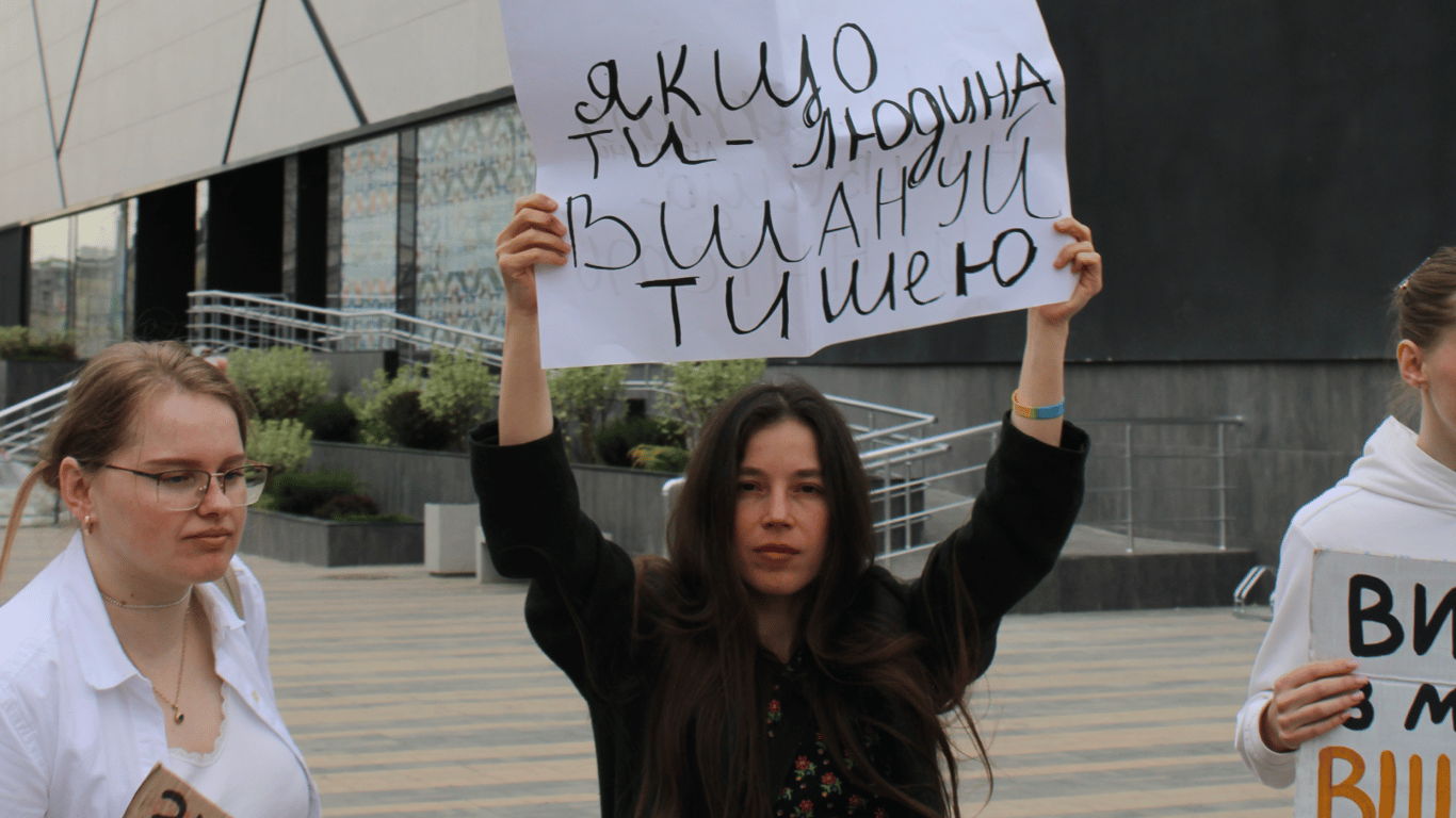 Плакат з закликом про вшанування у руках дівчини