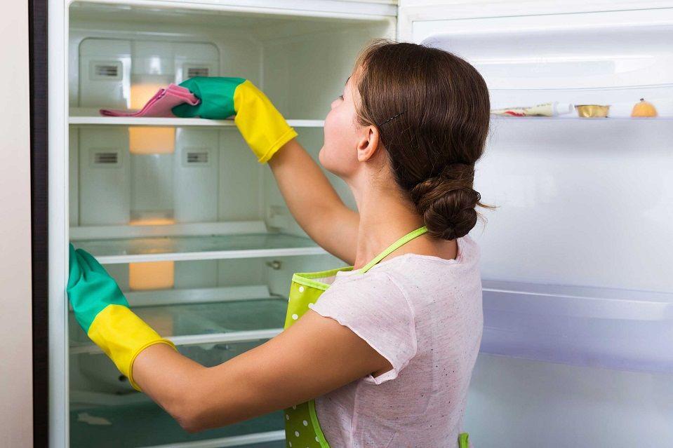 Женщина, которая очищает свой холодильник внутри