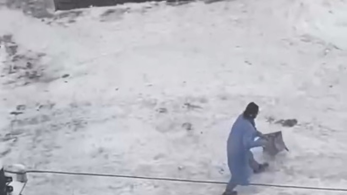 Женщина мыла шваброй снег у входа на почту в Киеве