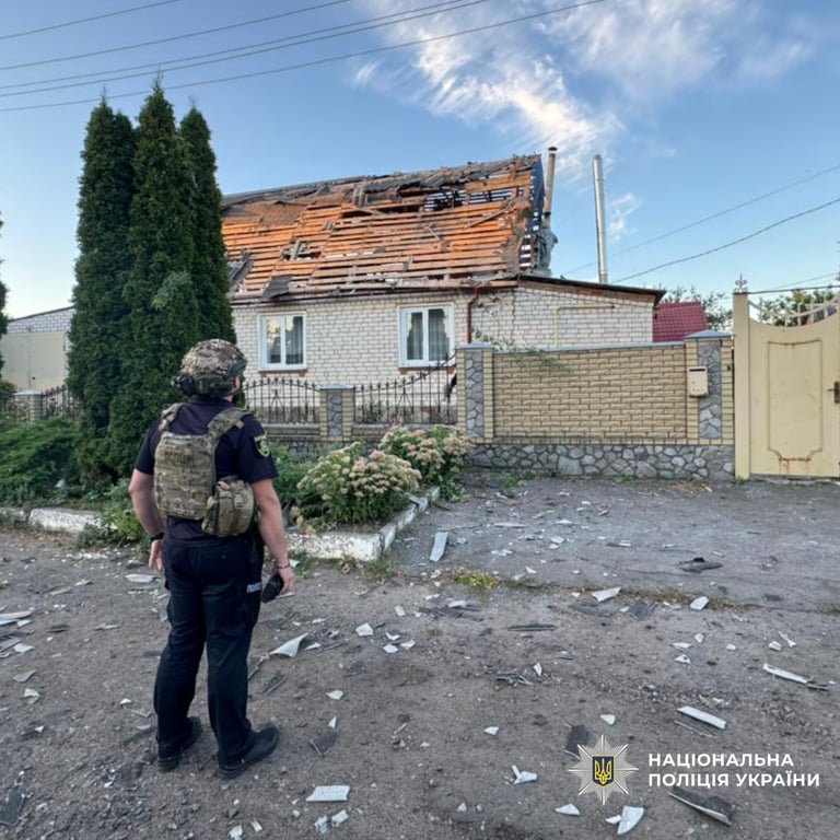 Поліцейський біля пошкодженого обстрілом будинку на Харківщині