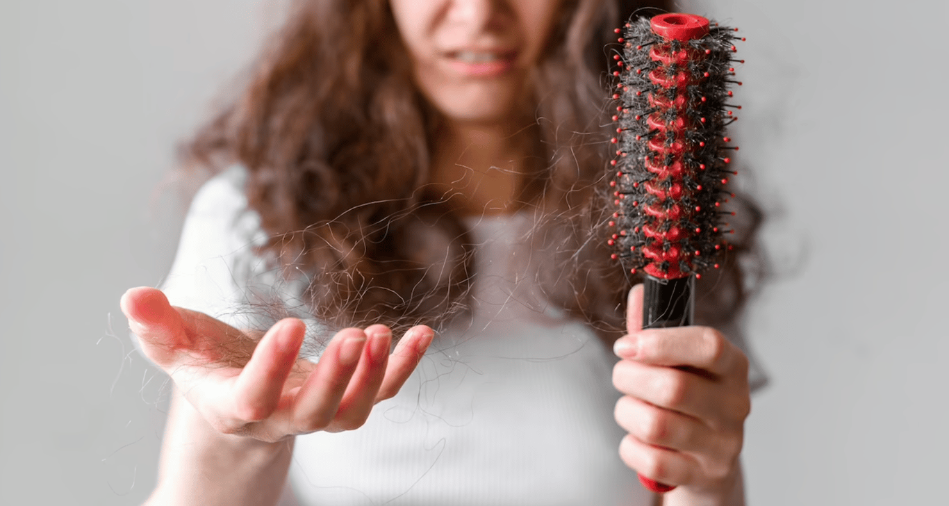 Девушка, которая держит расческу с кучей своих волос