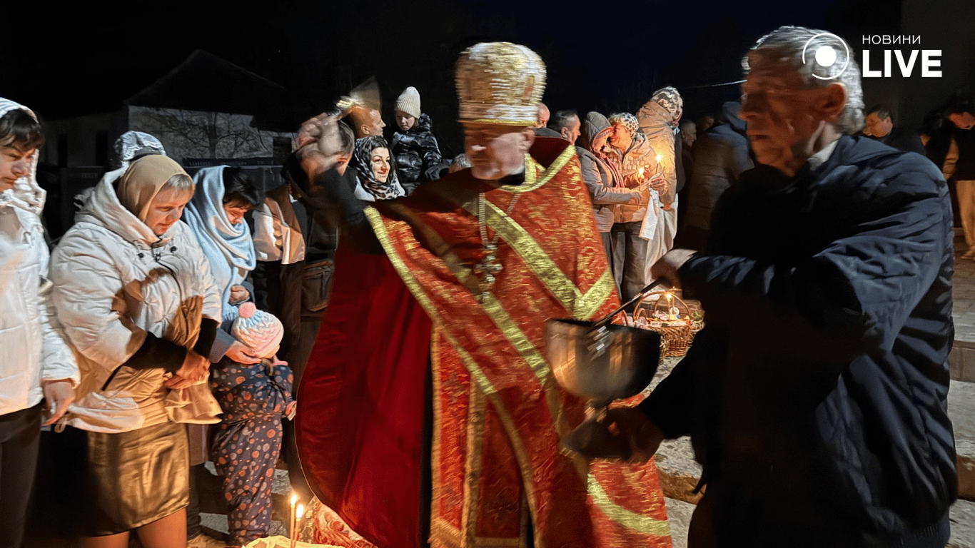 Священник освячує святкові кошики біля церкви