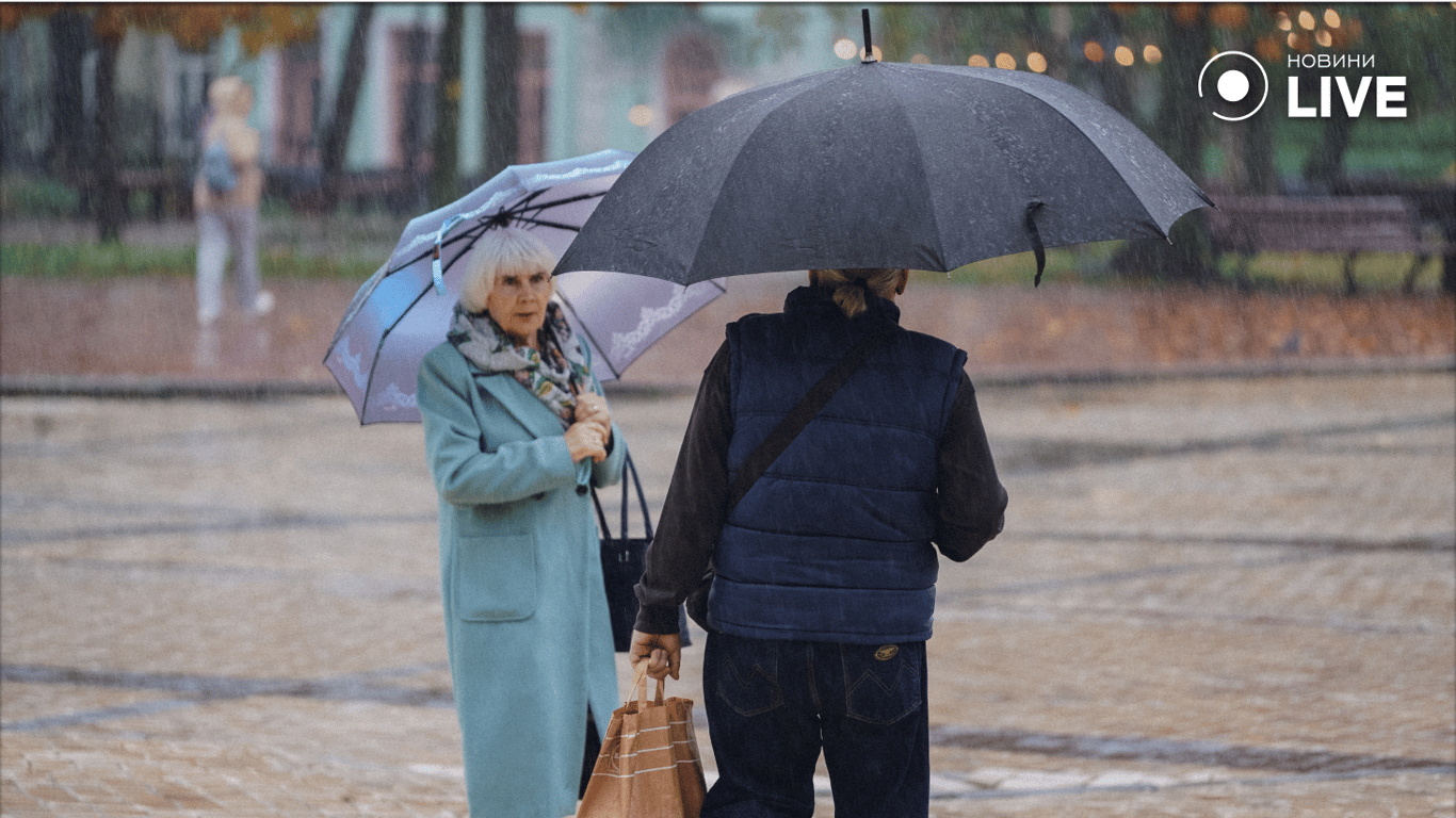 Люди прячутся под зонтиками от дождя