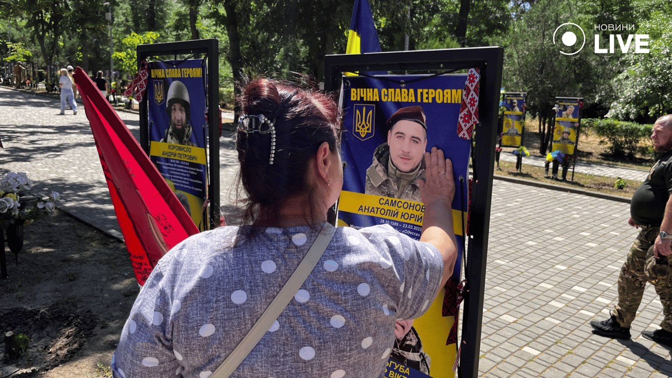 Жінка торкається портрета загиблого Героя на Алеї Героїв