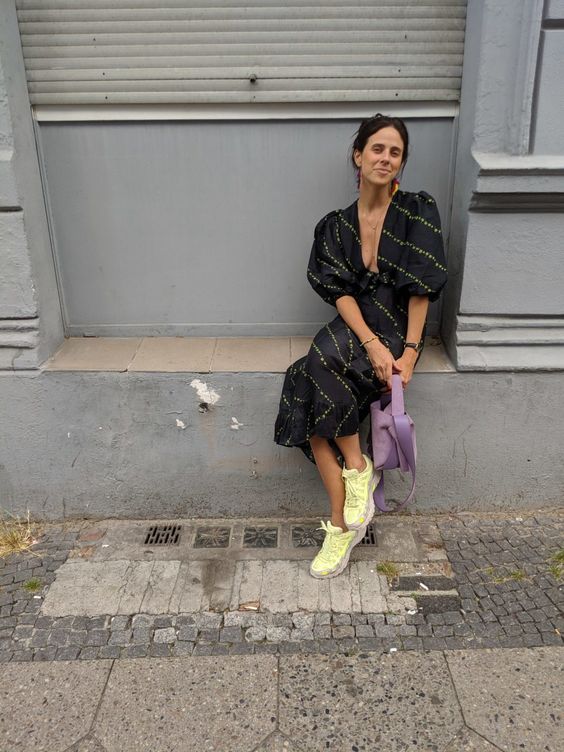 Женщина в темном платье и ярких кроссовках