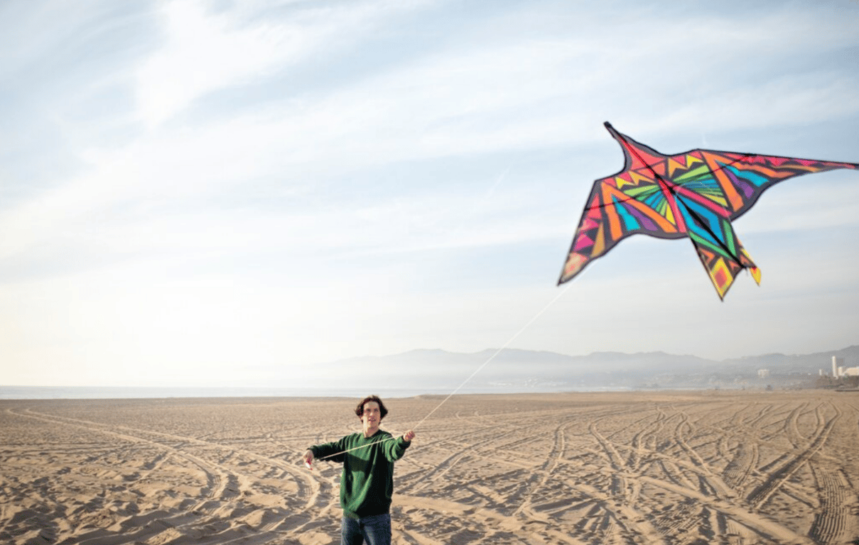 Молодой парень, который запускает воздушного змея