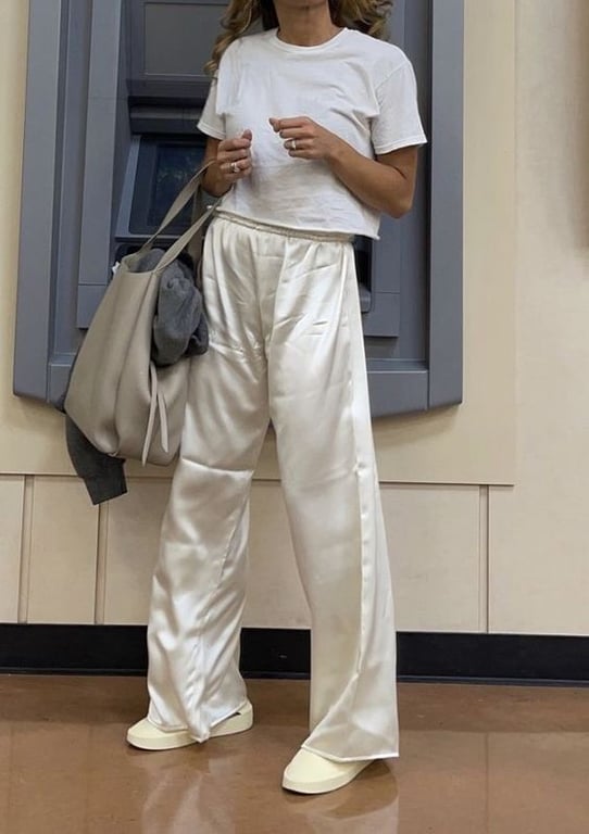 Женщина в шелковых брюках, футболке и кроссовках