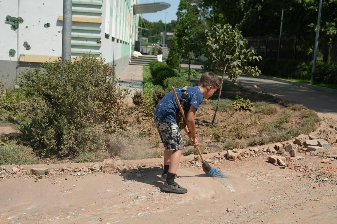 Дитина допомагає ліквідовувати наслідки російського обстрілу Києва 4 липня
