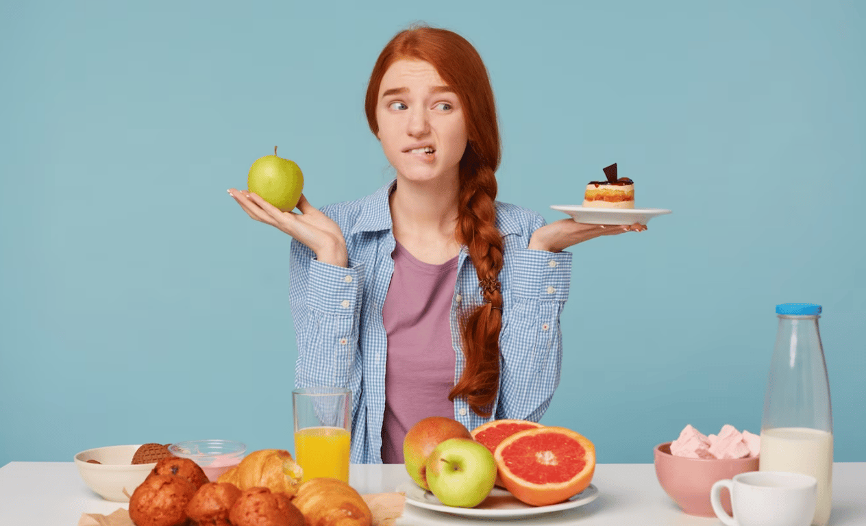 Молодая девушка, выбирающая между яблоком и пирожным.