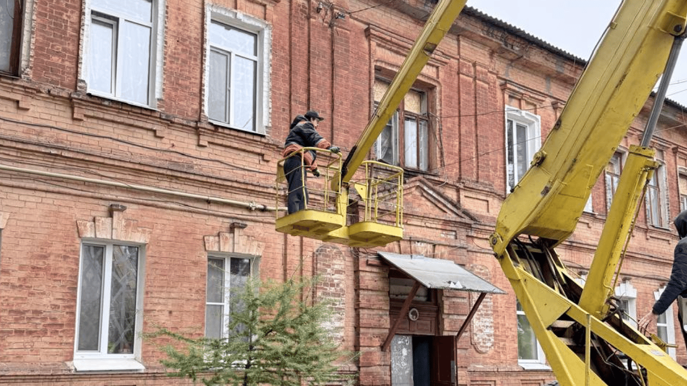 Комунальник працює на автовишці біля вікон цегляного багатоквартирного будинку в Харкові