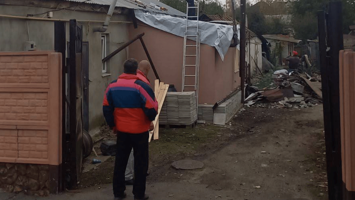 Працівники несуть дерев'яні дошки для ремонту пошкодженого приватного будинку в Харкові