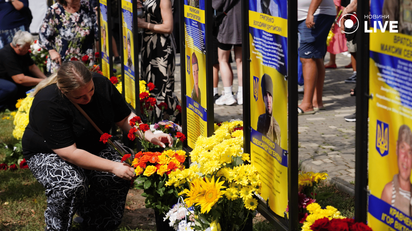 Жінка кладе квіти у памʼять про загиблого. Фото: Новини.LIVE