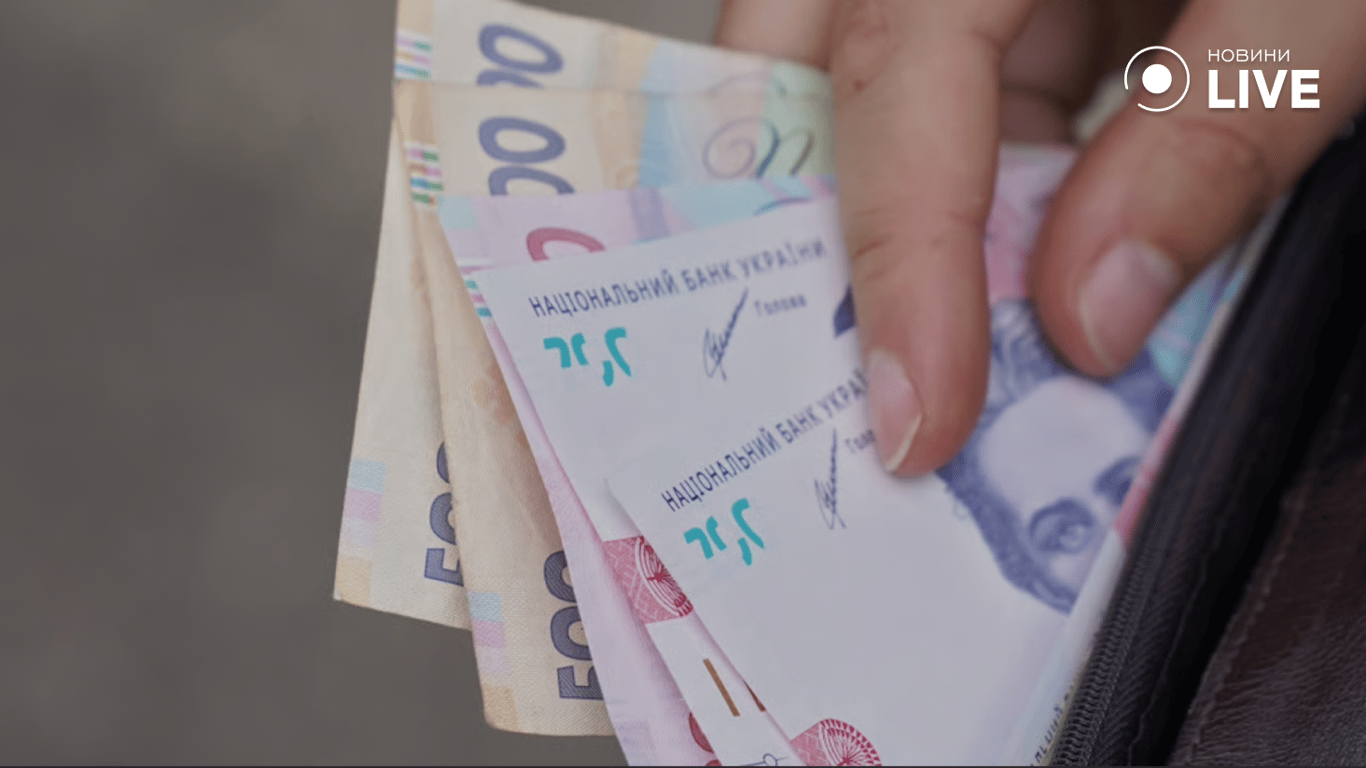 Людина дістає грошові купюри з гаманця