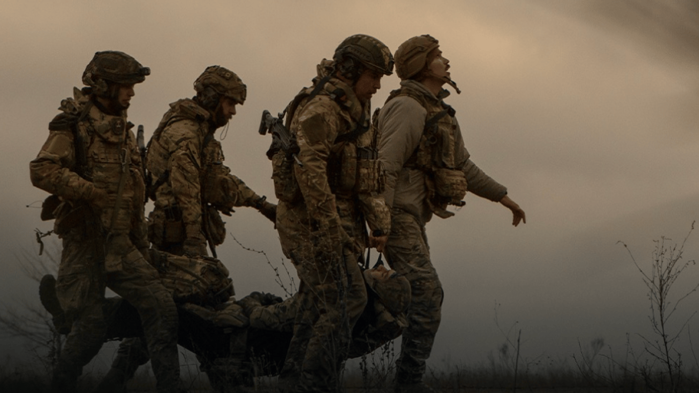 Військові несуть пораненого побратима 