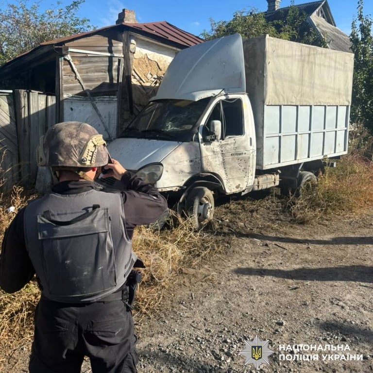 Поліцейський фотографує пошкоджену вантажівку біля будинку