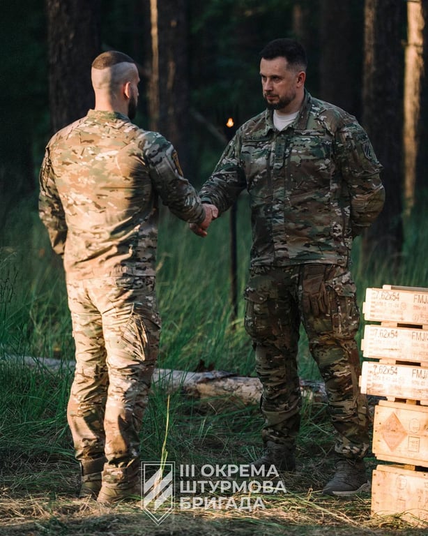 Командир Андрій Білецький вручає підлеглим пам'ятні коїни