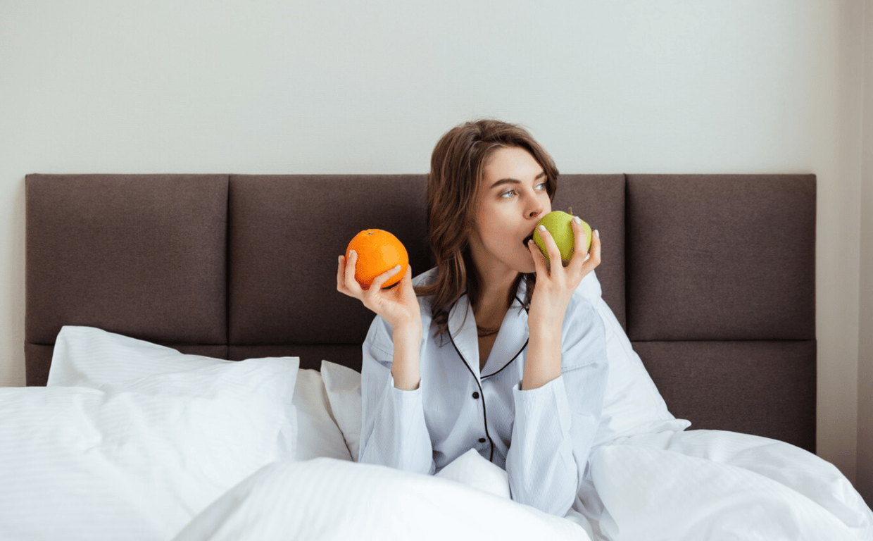 Женщина, употребляющая яблоко и апельсин