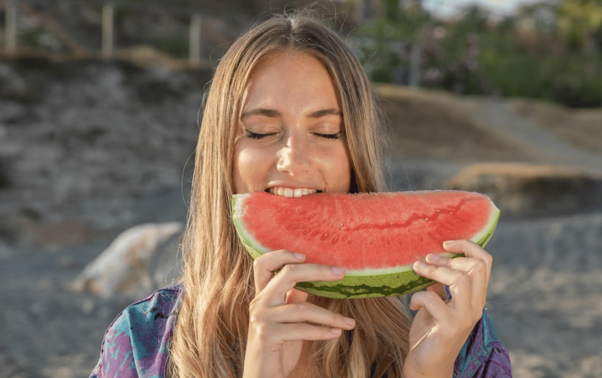 Молодая девушка, которая употребляет арбуз летом