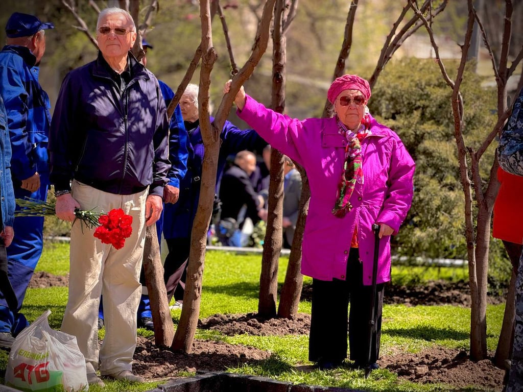 Жінка стоїть в тіні під час покладання квітів