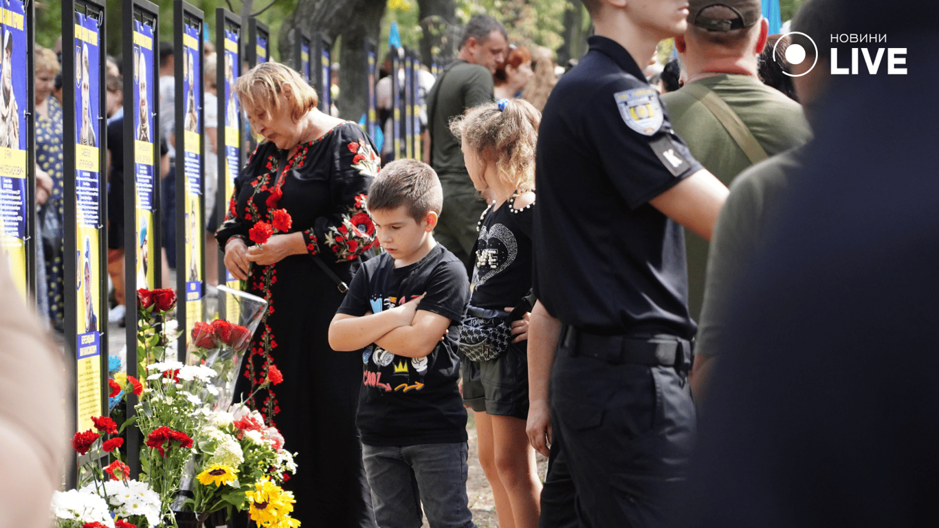 Хлопчик дивиться на памʼятну табличку про тата. Фото: Новини.LIVE