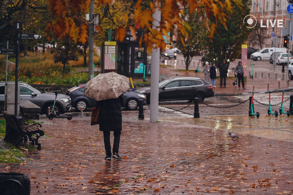 Жінка під парасолею на тлі осіннього Києва