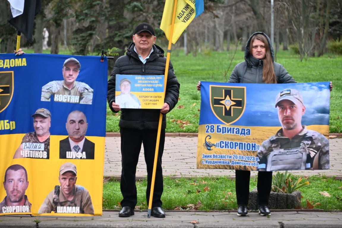 Люди з саморобними плакатами стоять біля будівлі облради.