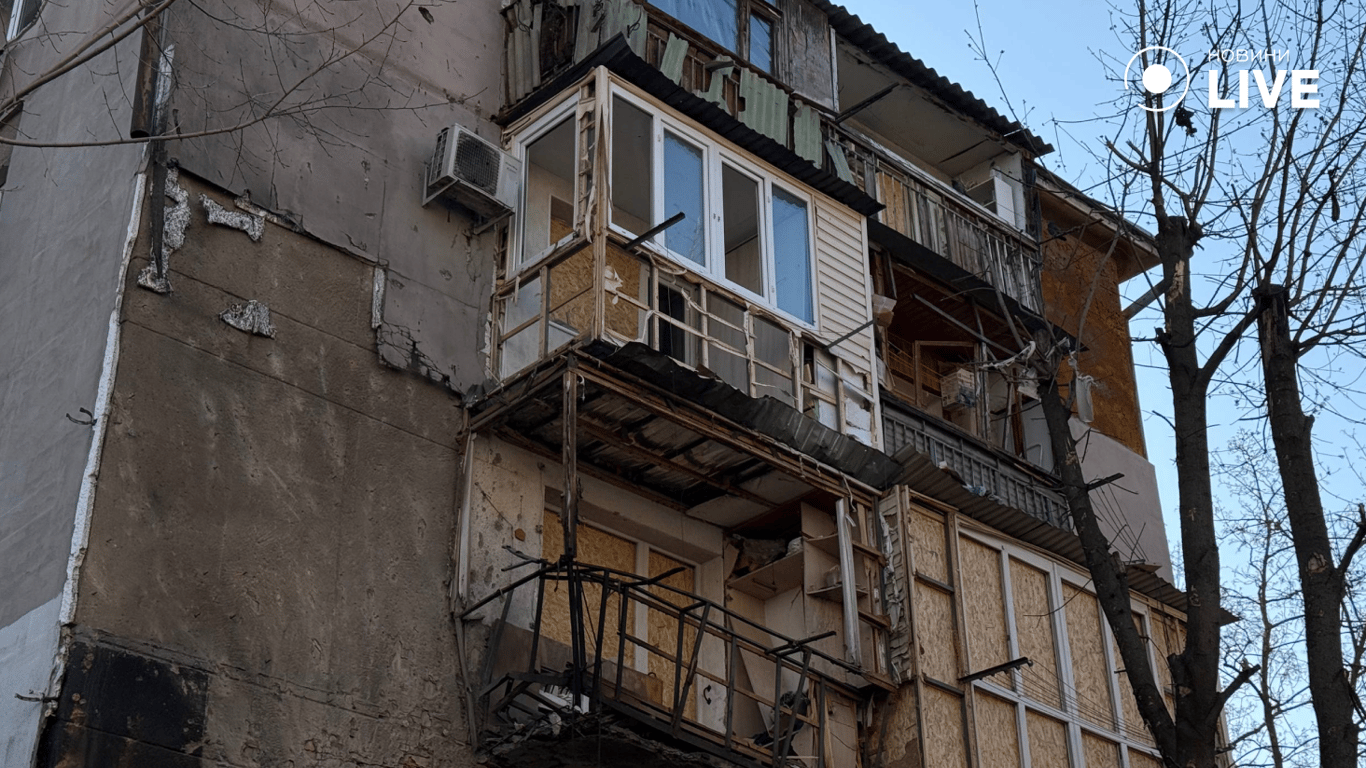 Забиті фанерою вікна будинку, який постраждав від обстрілу