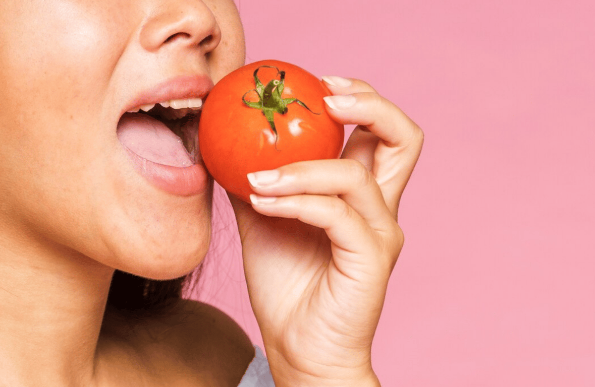 Женщина, которая ест помидор