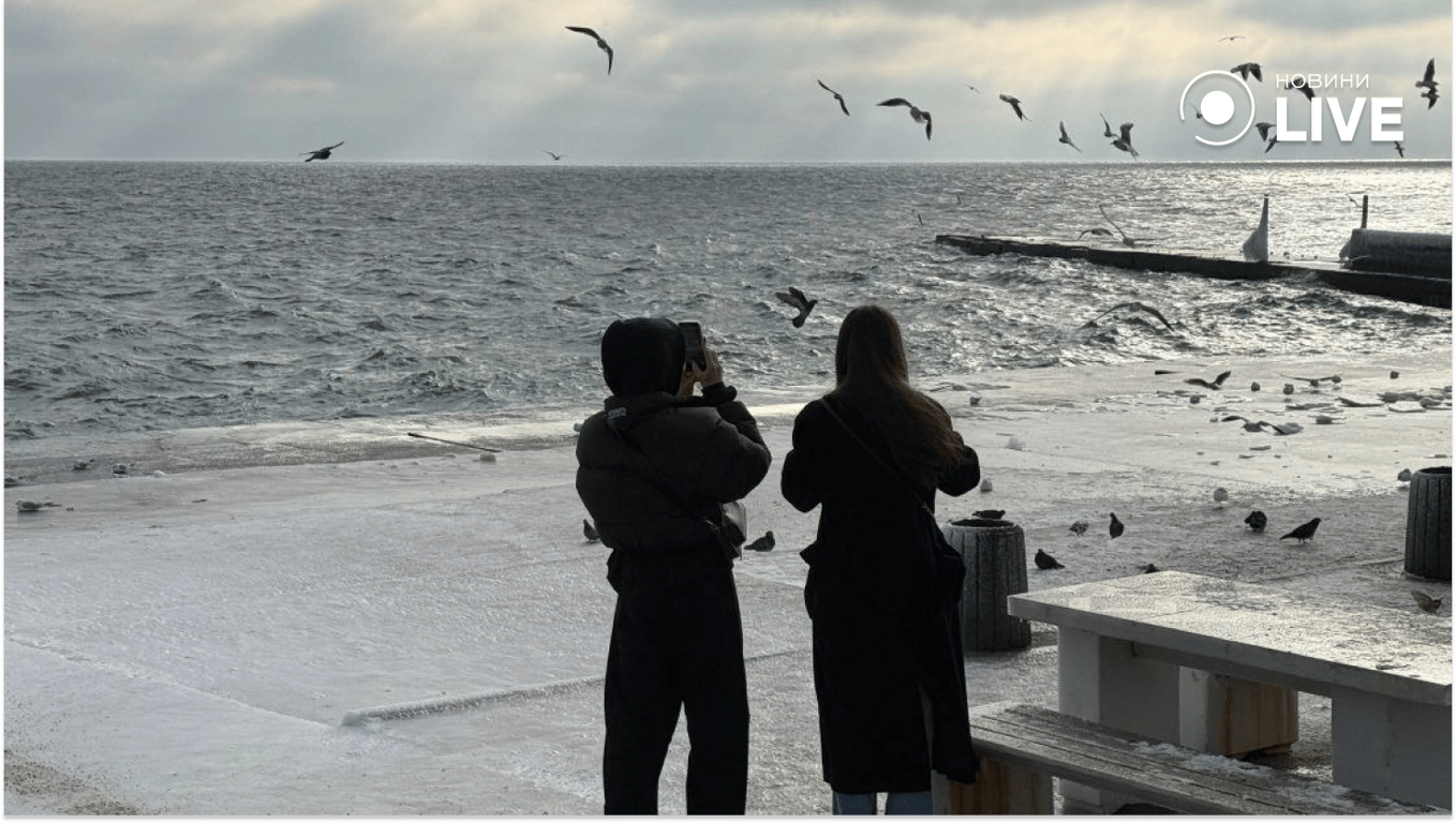 Люди гуляють зимовим узбережжям